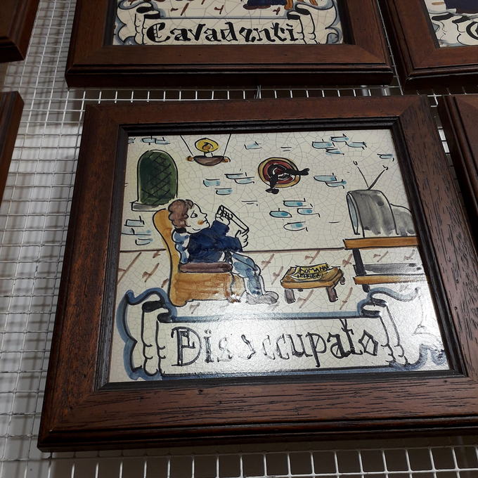 Mattonelle di ceramica dipinta incorniciate al muro, con le figure dei vecchi mestieri: il «Disoccupato» e il «Cavadenti».